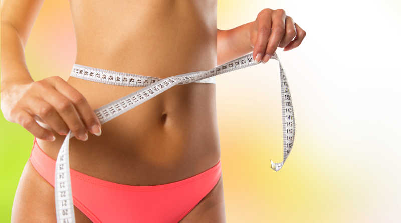 苗条的测量腰围的年轻女人