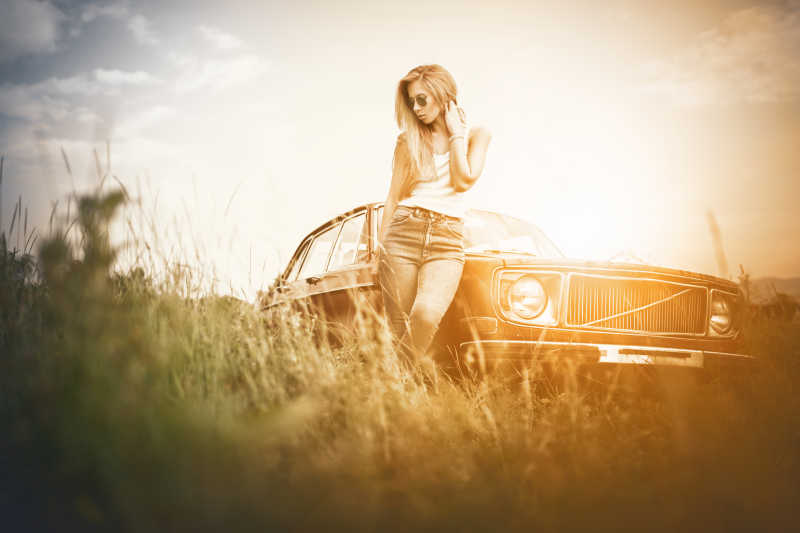 旧时代车旁的时尚年轻女性