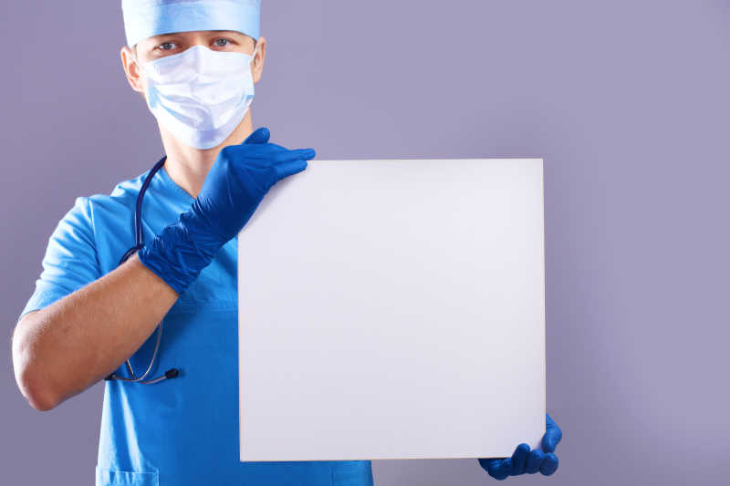 面罩里的外科医生拿着标语牌