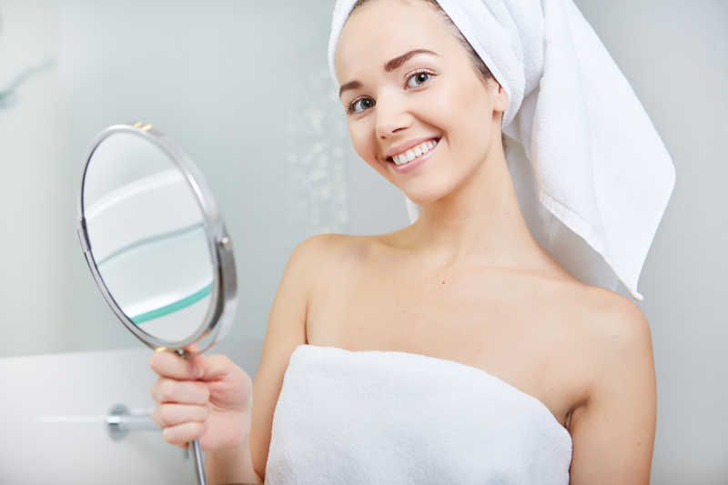 看镜子的浴室里的年轻女人