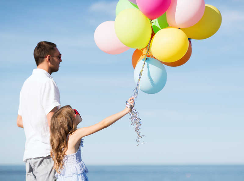 带着彩色气球的小女孩和父亲在一起