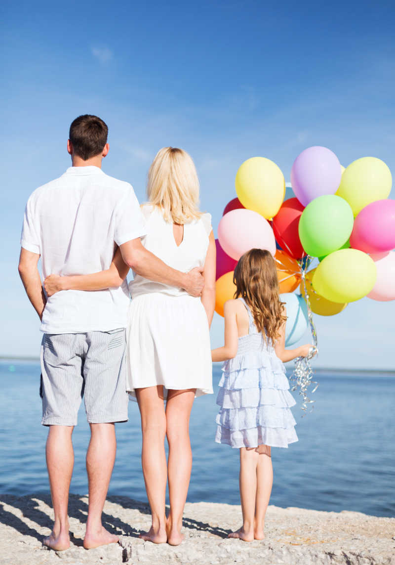 海边的一家人带着彩色气球