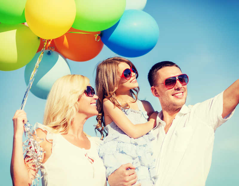 开心微笑的一家人手拿五颜六色的气球