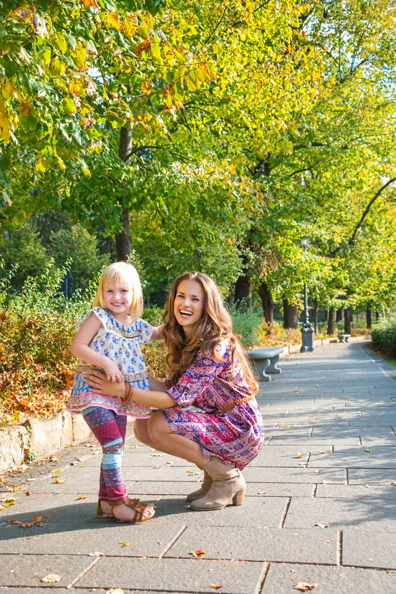 在公园里散步的年轻妈妈和小女孩