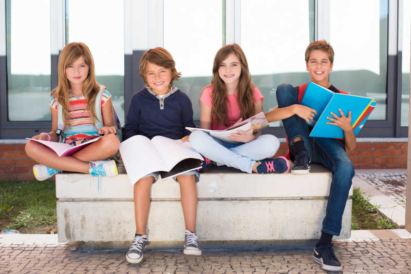 坐在校园石椅上的开心的学生