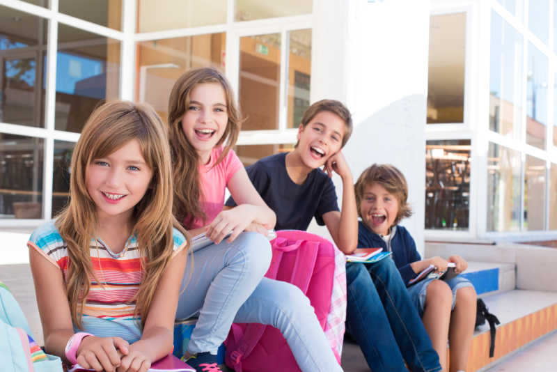 坐在室外的台阶上的四个小学生