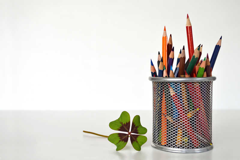 白色背景下的四叶草和彩色铅笔