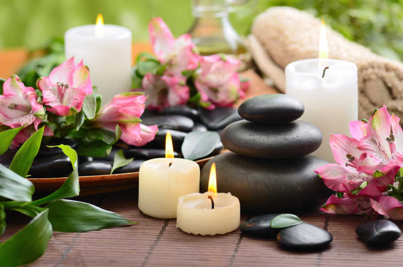 褐色竹帘上的香薰蜡烛和黑色石头上的花朵