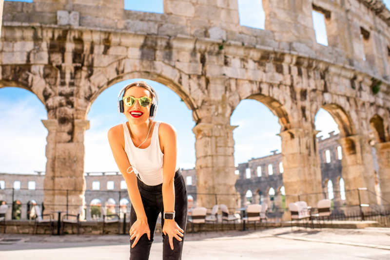 建筑前戴着墨镜听音乐的美女