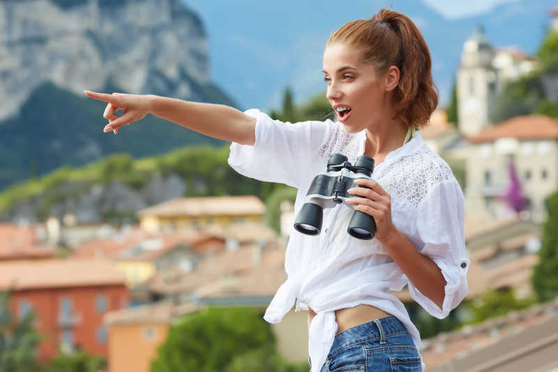 可爱的暑假旅游的妇女在户外用双筒望远镜看