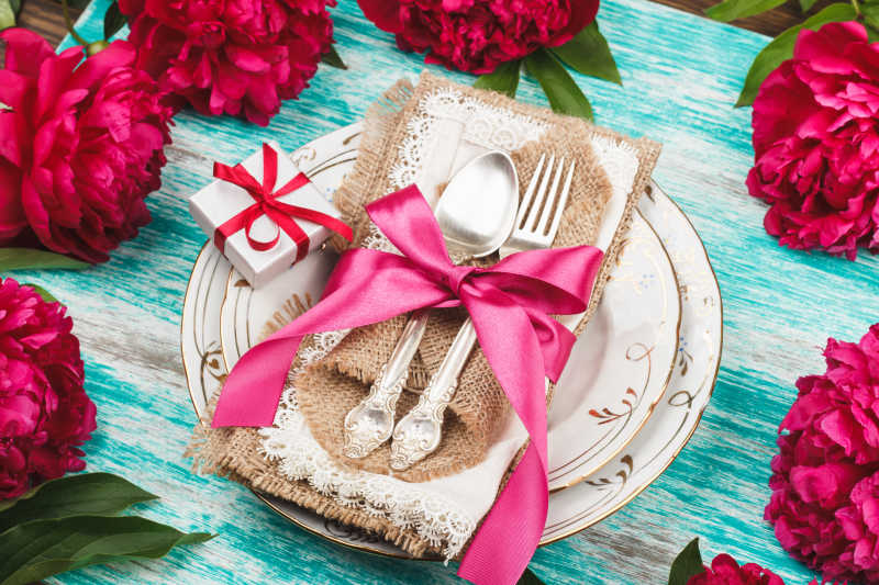 浅蓝背景的红肉牡丹餐具和银器