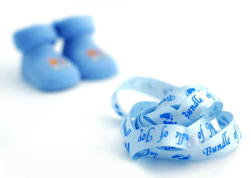 白色背景下的蓝色婴儿鞋子和皮尺