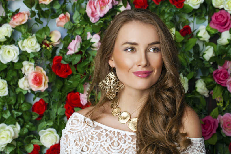 花墙前面的微笑的白裙美女