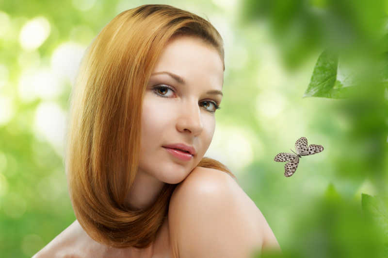 绿色自然模糊背景上的漂亮金发女人