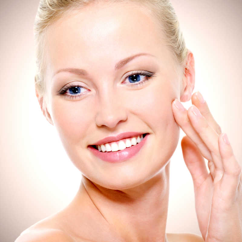 白色背景下手抚摸自己的脸部的微笑的美女