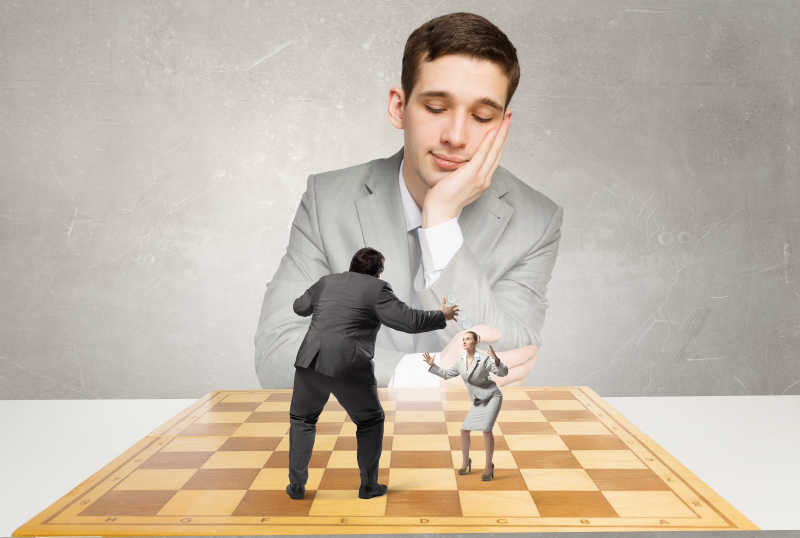 商人坐在桌子边观看在棋盘上搏斗的人