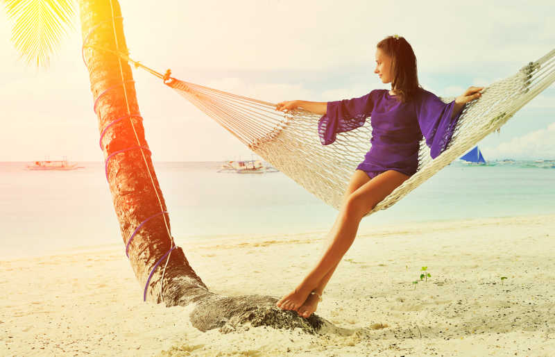 坐在海滩吊床上看风景的美女