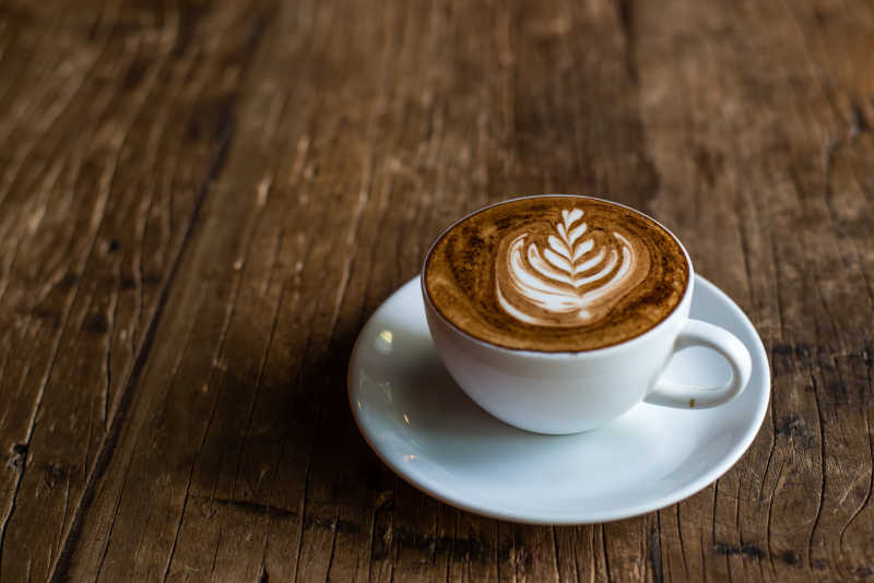 木桌子上放着一杯花式咖啡