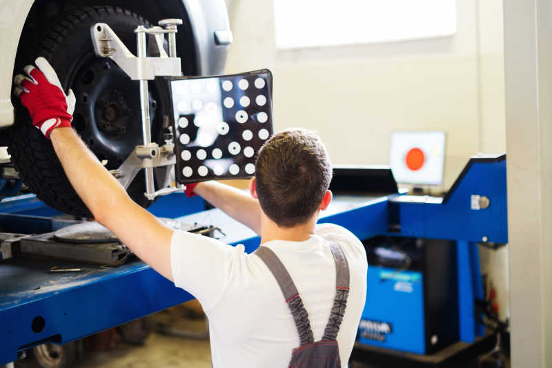 工人拿着工具进行汽车轮胎定位