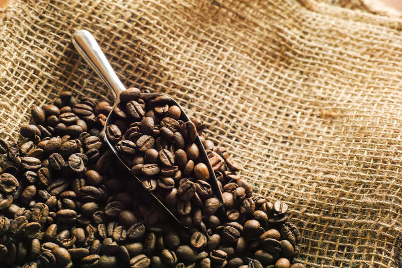亚麻布上勺子里的咖啡豆