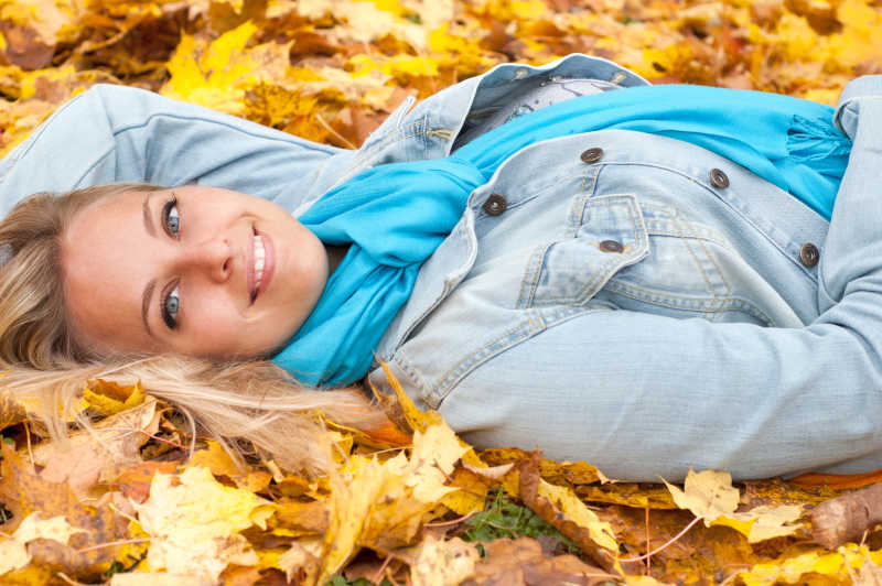 秋天森林里美丽的年轻女子躺在叶子上
