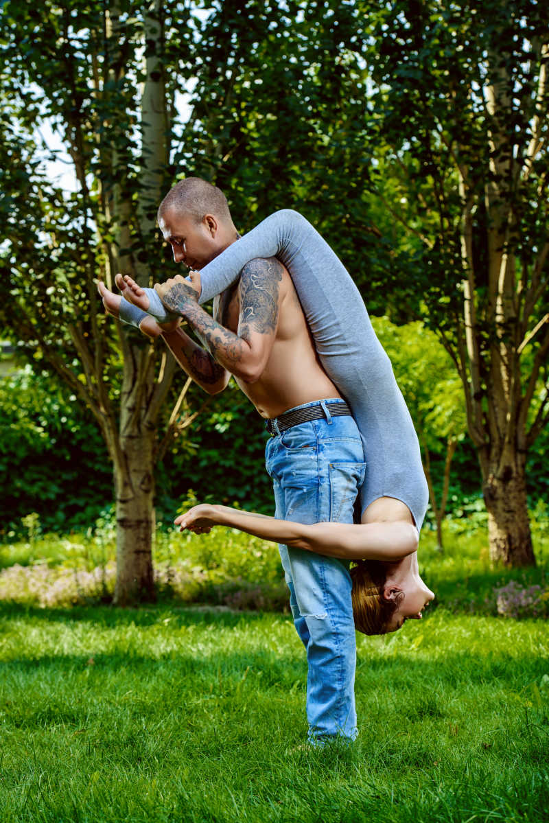 年轻情侣一起在户外做情侣瑜伽运动