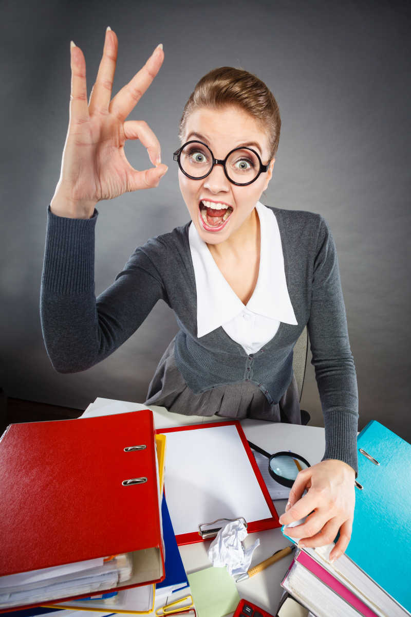 在办公桌上愉快的办公室小姐在做OK手势