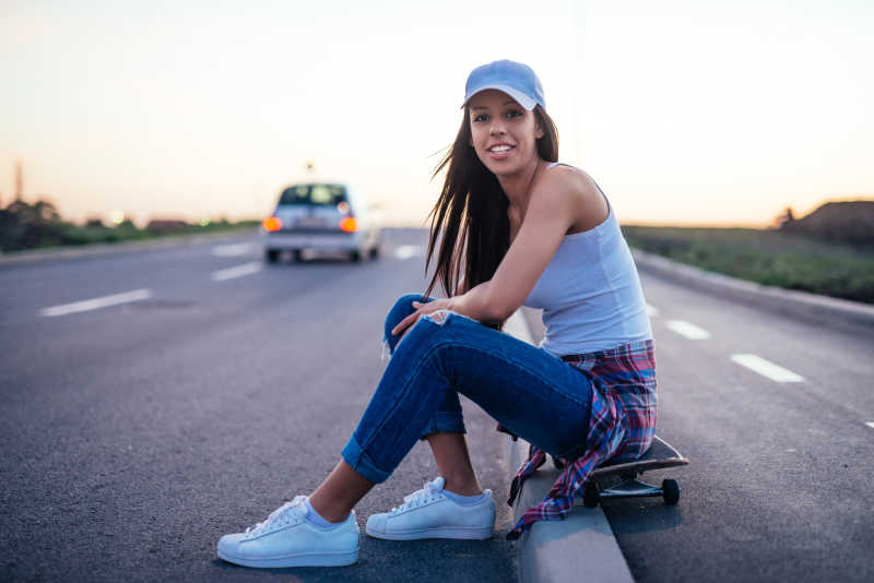 女孩在户外坐在滑板上休息