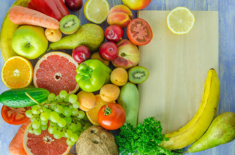 木桌案板旁边的香蕉柠檬西红柿梨柠檬柚子葡萄胡萝卜俯视摄影