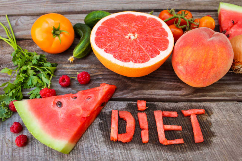 木桌上新鲜的西瓜柚子桃子西红柿