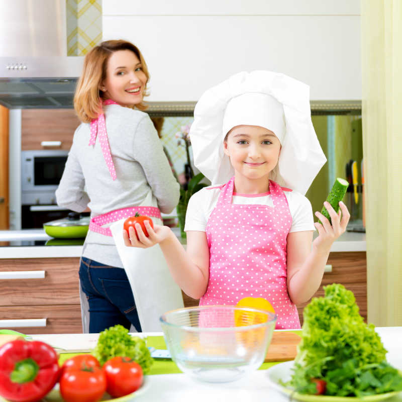小女孩在厨房拿着黄瓜和番茄