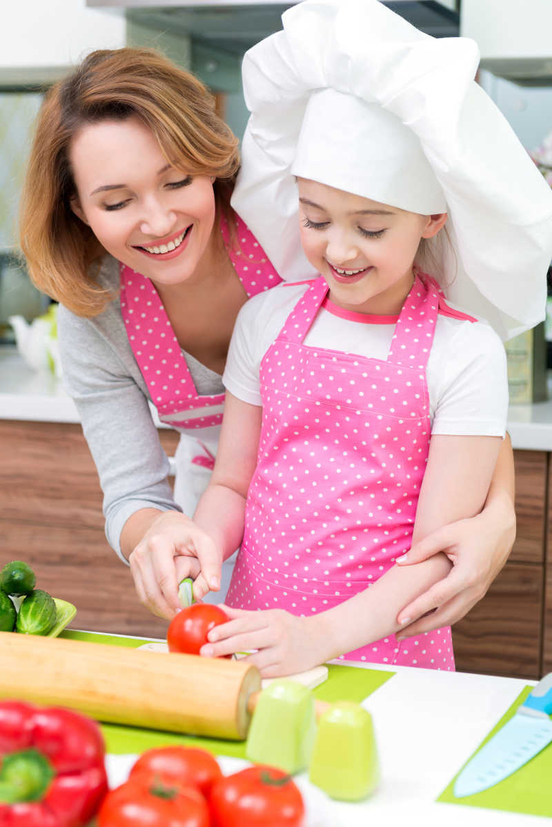 小女孩和母亲在厨房切番茄