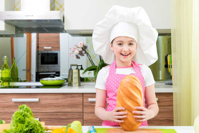 小女孩在厨房拿着一个超大的面包