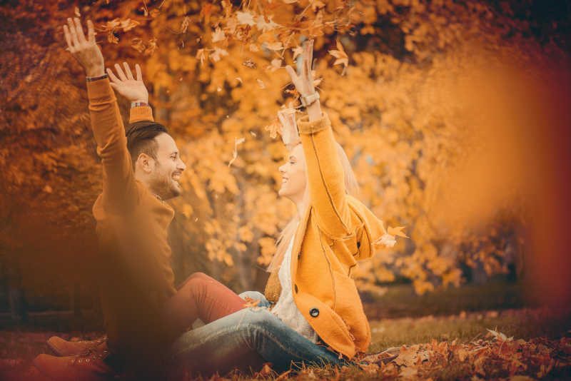 年轻的美满情侣在秋天的公园里玩得很开心