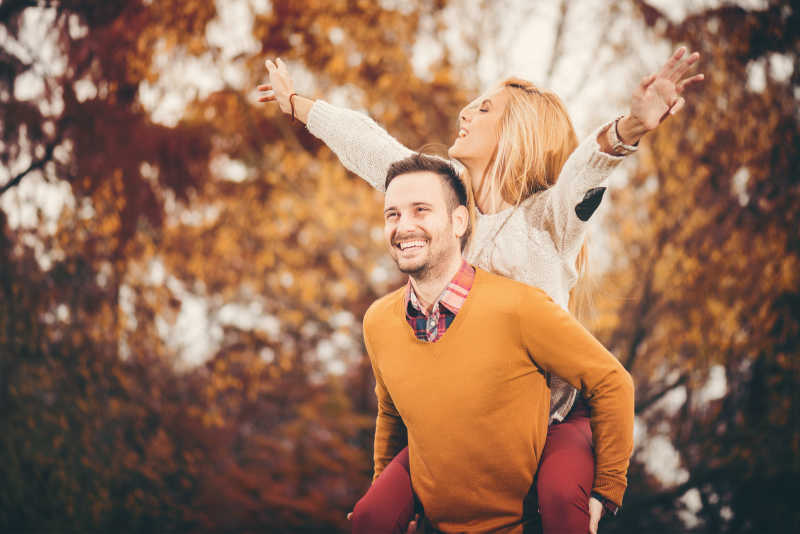 年轻的美满夫妇在秋天的公园里玩得很开心