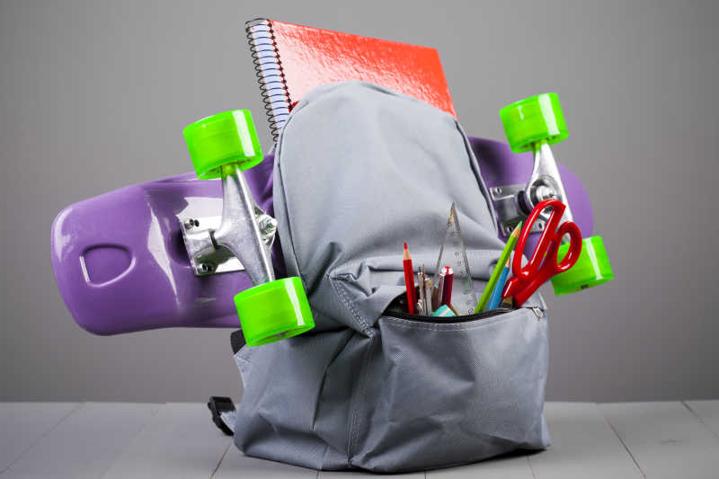 灰色双肩包中的学习用品和滑板