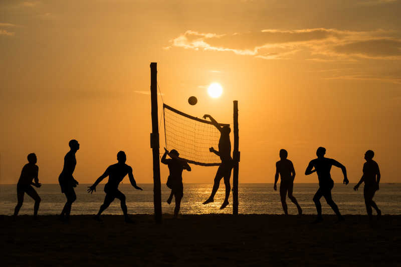 夕阳沙滩上沙滩排球运动员的剪影