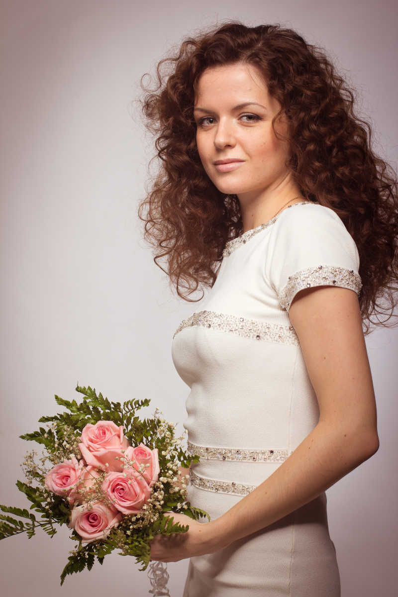 手拿粉红色玫瑰的美丽的白种女人