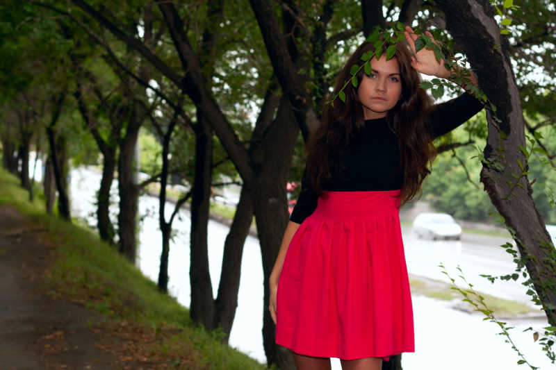 穿着红色连衣裙的美女在公园的小巷