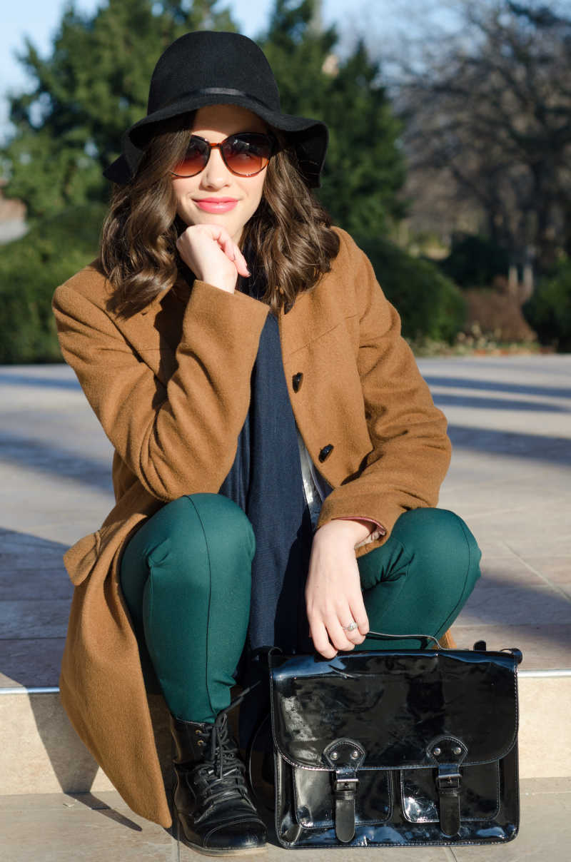 美丽的时尚女孩坐在阳光明媚的秋日公园里