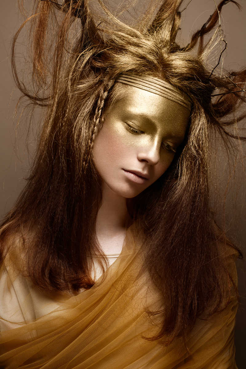 棕色背景前的金色艺术妆容美女