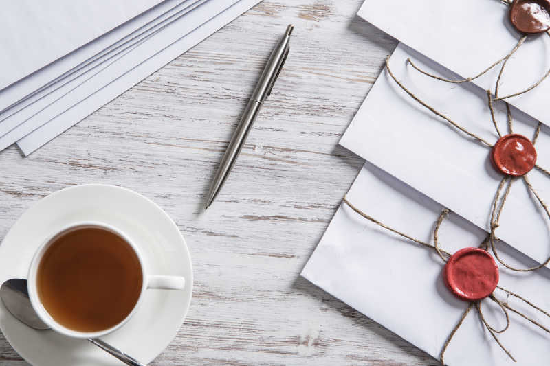 木纹理桌上的咖啡和信封还有钢笔