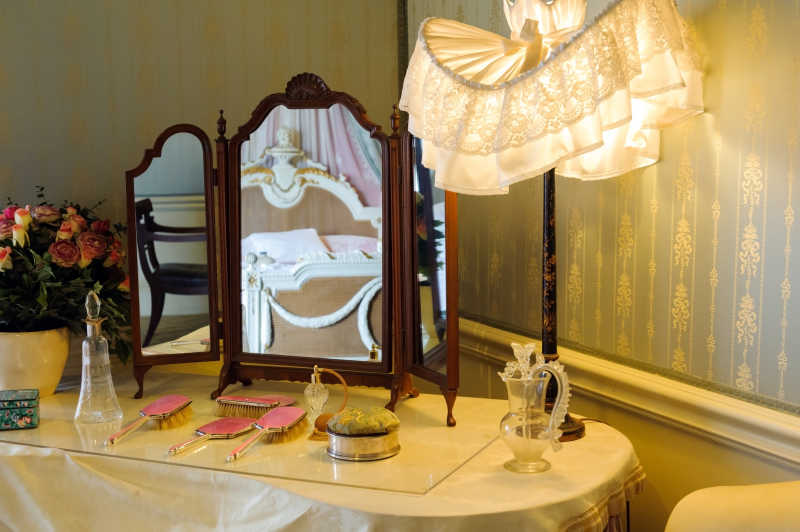 黄色灯光下有棕色镜子和粉色梳子的化妆台