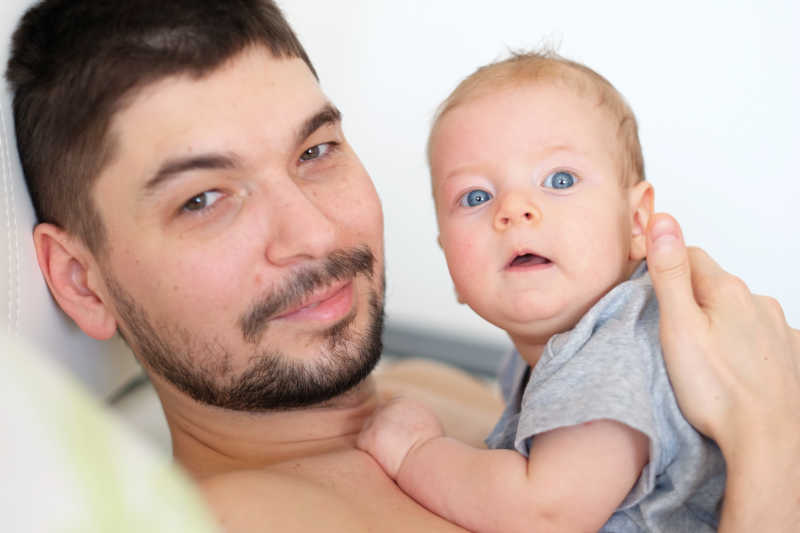 抱着新生儿看镜头的父亲