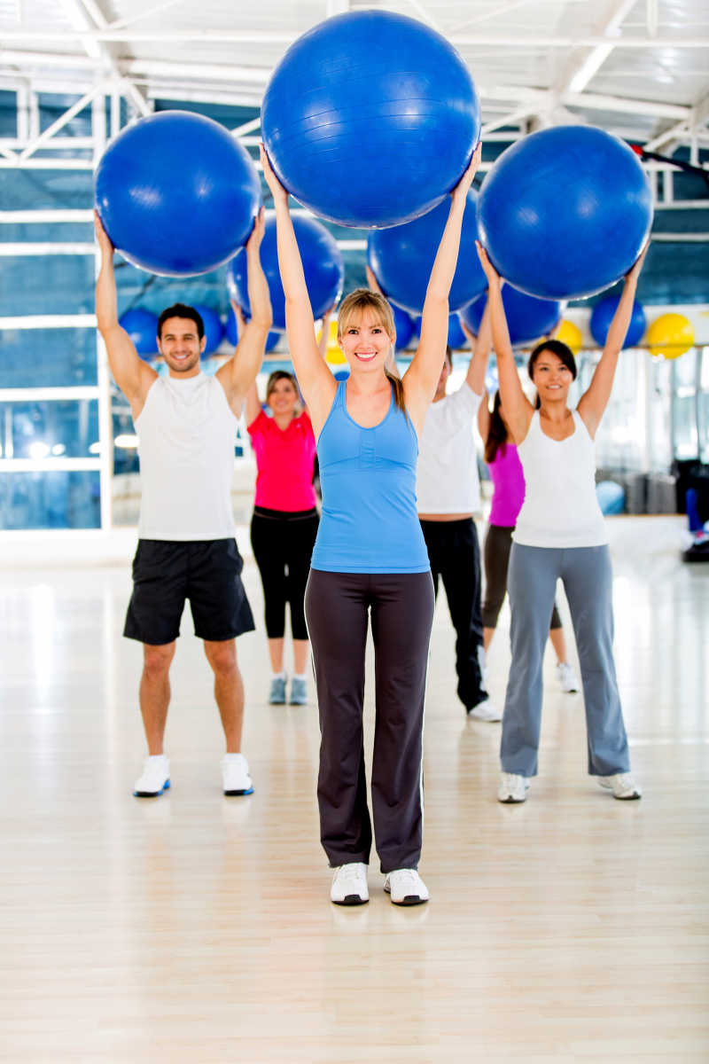 六个男女在举着瑜伽球锻炼身体