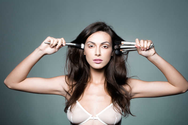 双手拿化妆刷的漂亮女子