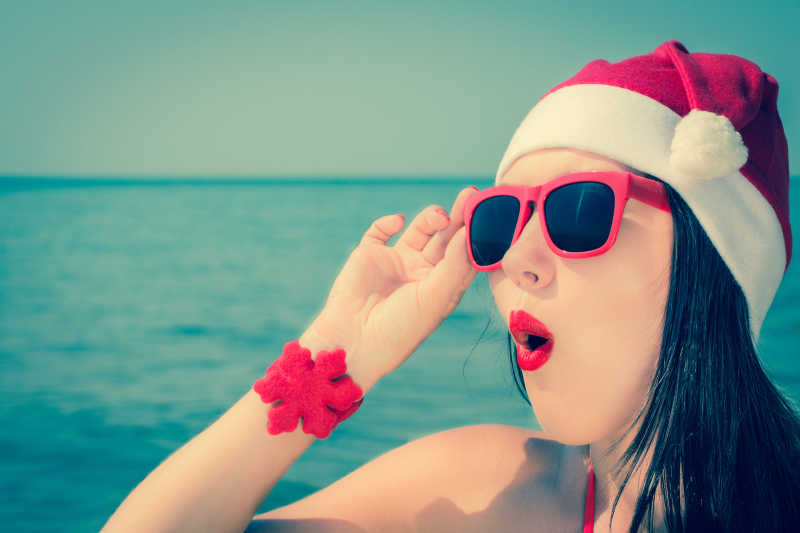 时尚美女带着圣诞帽子和墨镜