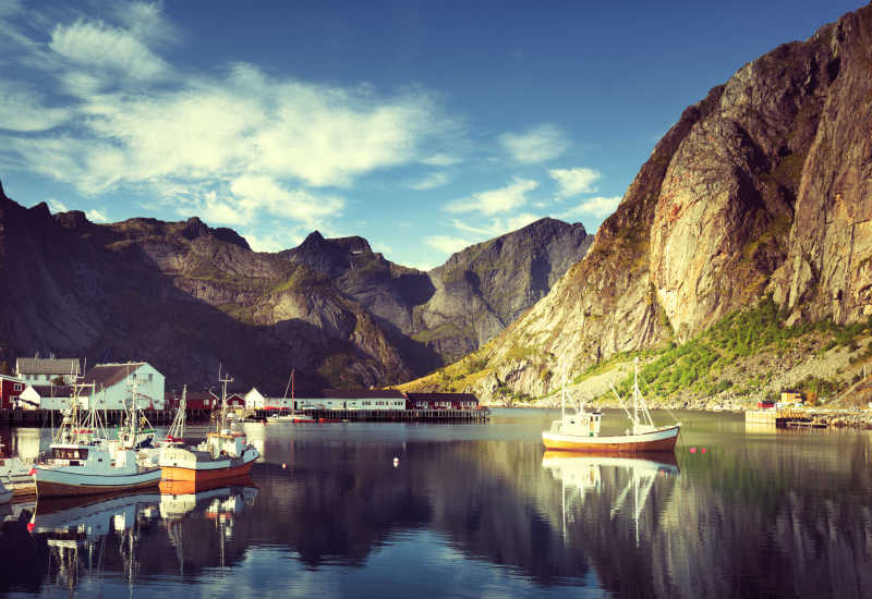蓝天白云背景下罗弗敦群岛之群山之中的湖泊上的船只