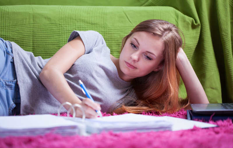 躺在地毯上学习的女孩