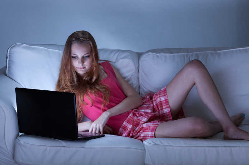 靠在沙发上玩电脑的美女